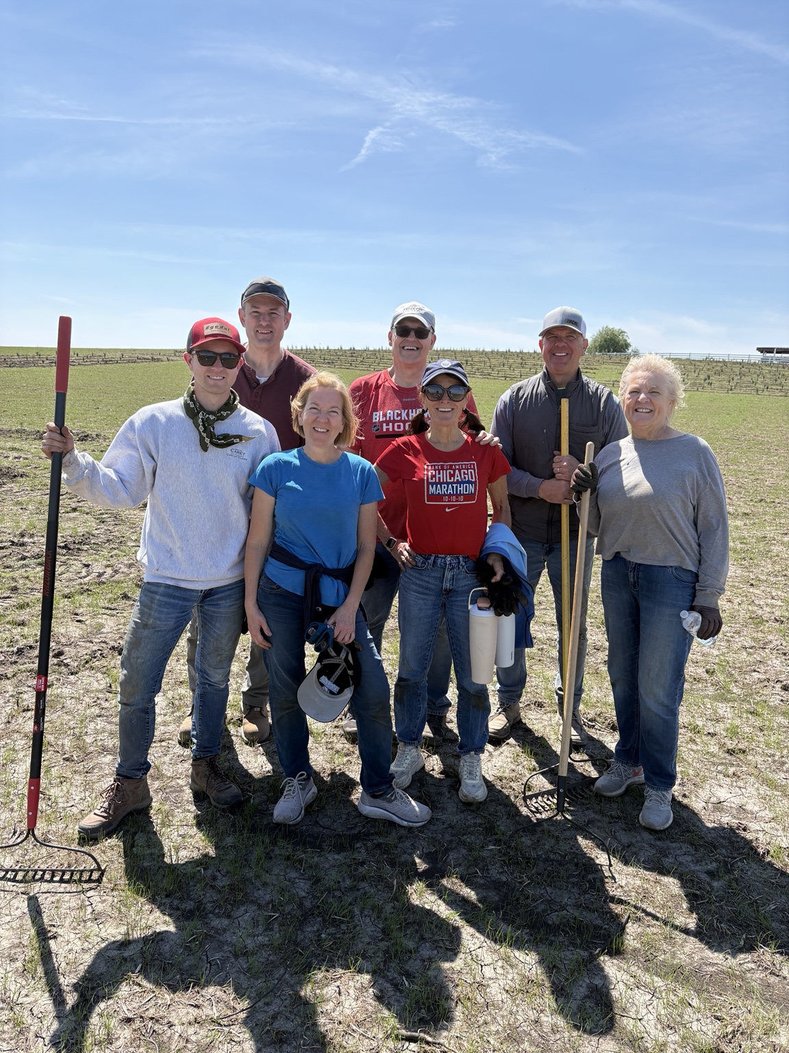 Family and friends standing together with rakes in the freshly planted field
